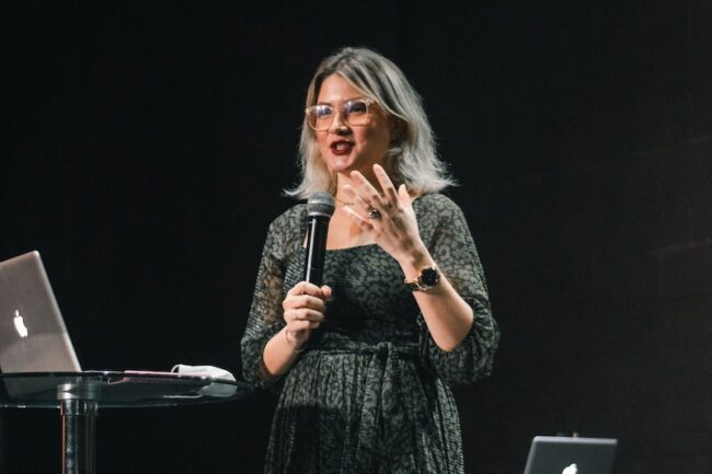 A Woman Talking on the Microphone while on Stage